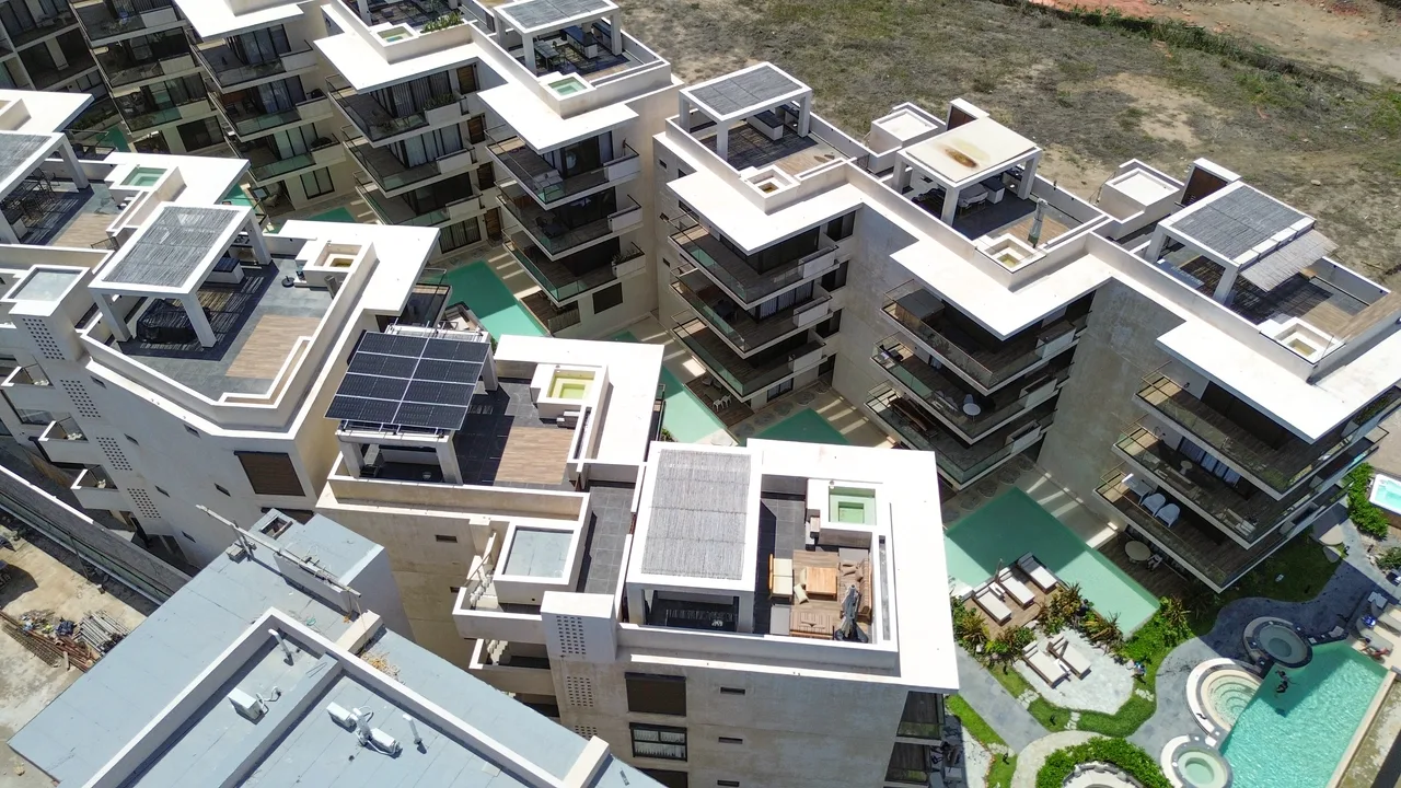 Vista aérea de los bloques de Aldea Ananta en formación de V, con la alberca central y los rooftops privados frente al mar.