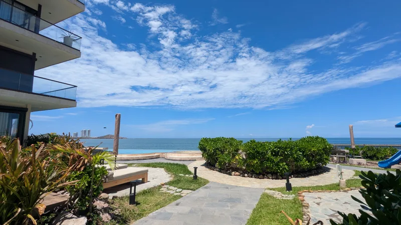 Vista desde la terraza Vista desde una terraza de Aldea Ananta hacia el mar, con la alberca del conjunto y el perfil de Mazatlán al fondo.