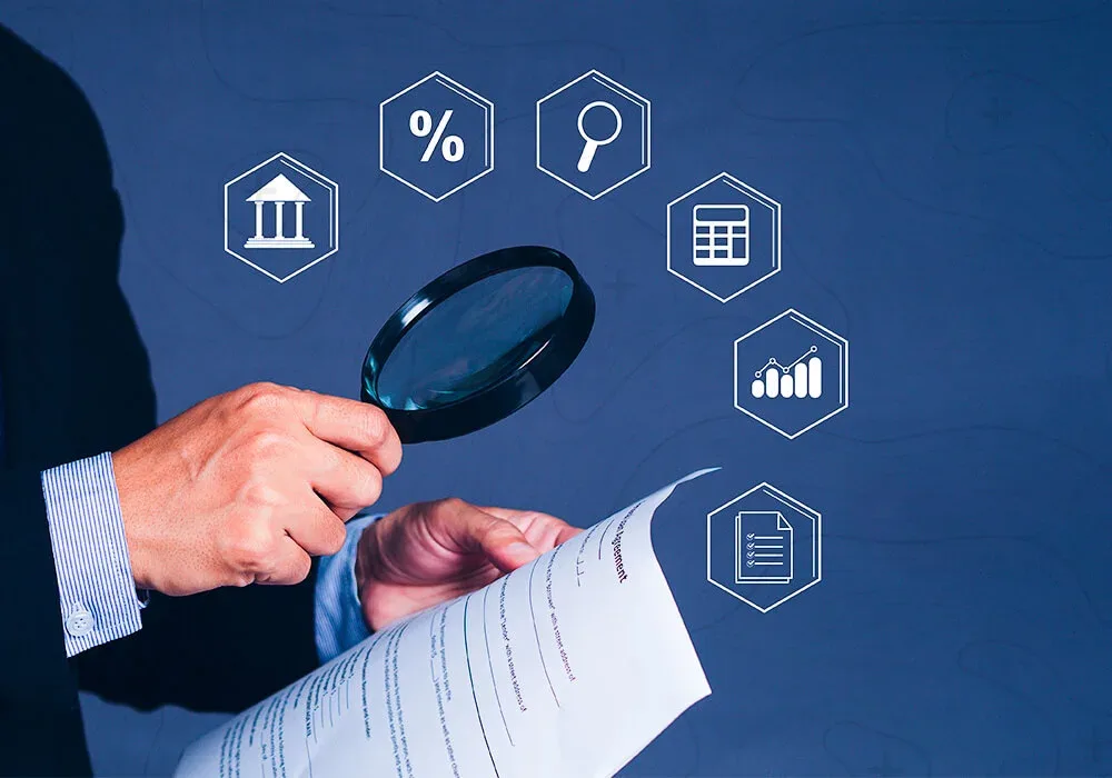 Mano con lupa revisando un documento, rodeada de iconos de conceptos financieros