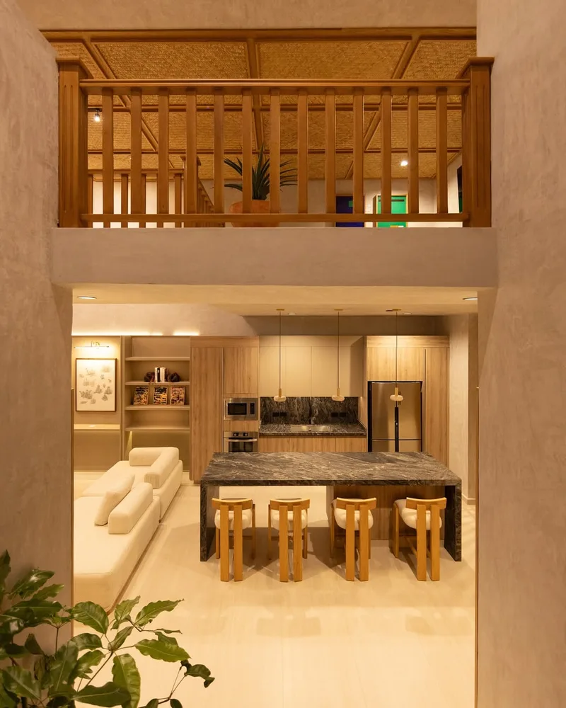 Espacio de doble altura con mezzanine de celosia de madera sobre la cocina y su isla