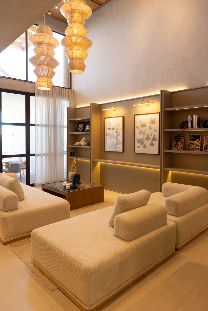 Sala de la villa muestra con lamparas colgantes de papel, sofas beige y librero integrado de madera