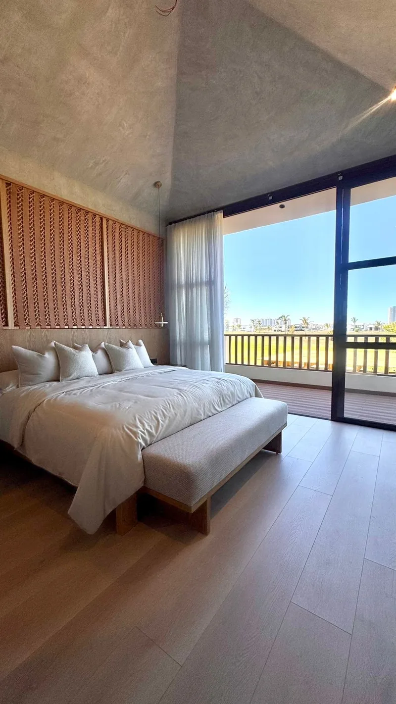 Recamara principal con cabecera acanalada y ventanal hacia la marina