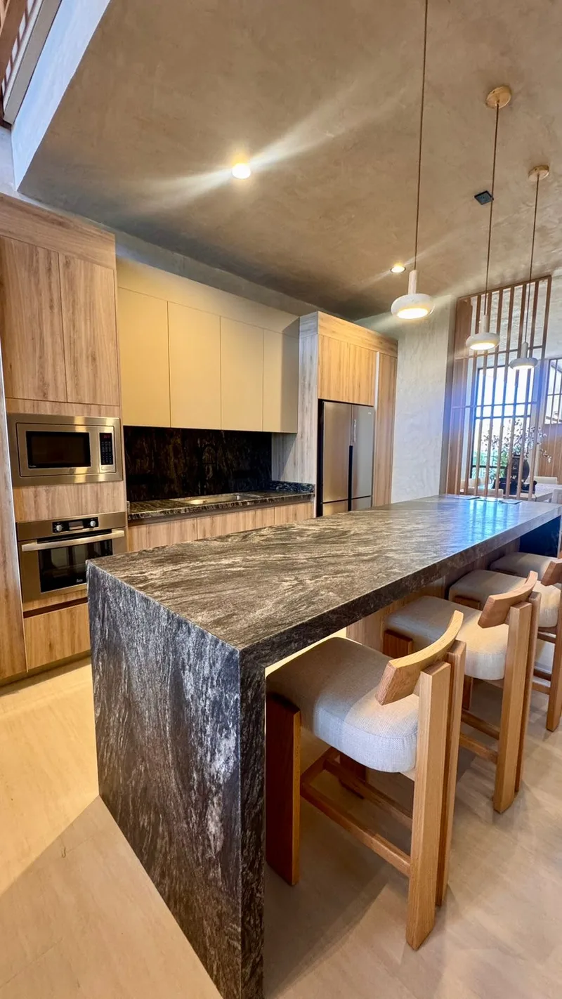 Cocina con isla de piedra veteada y bancos de madera