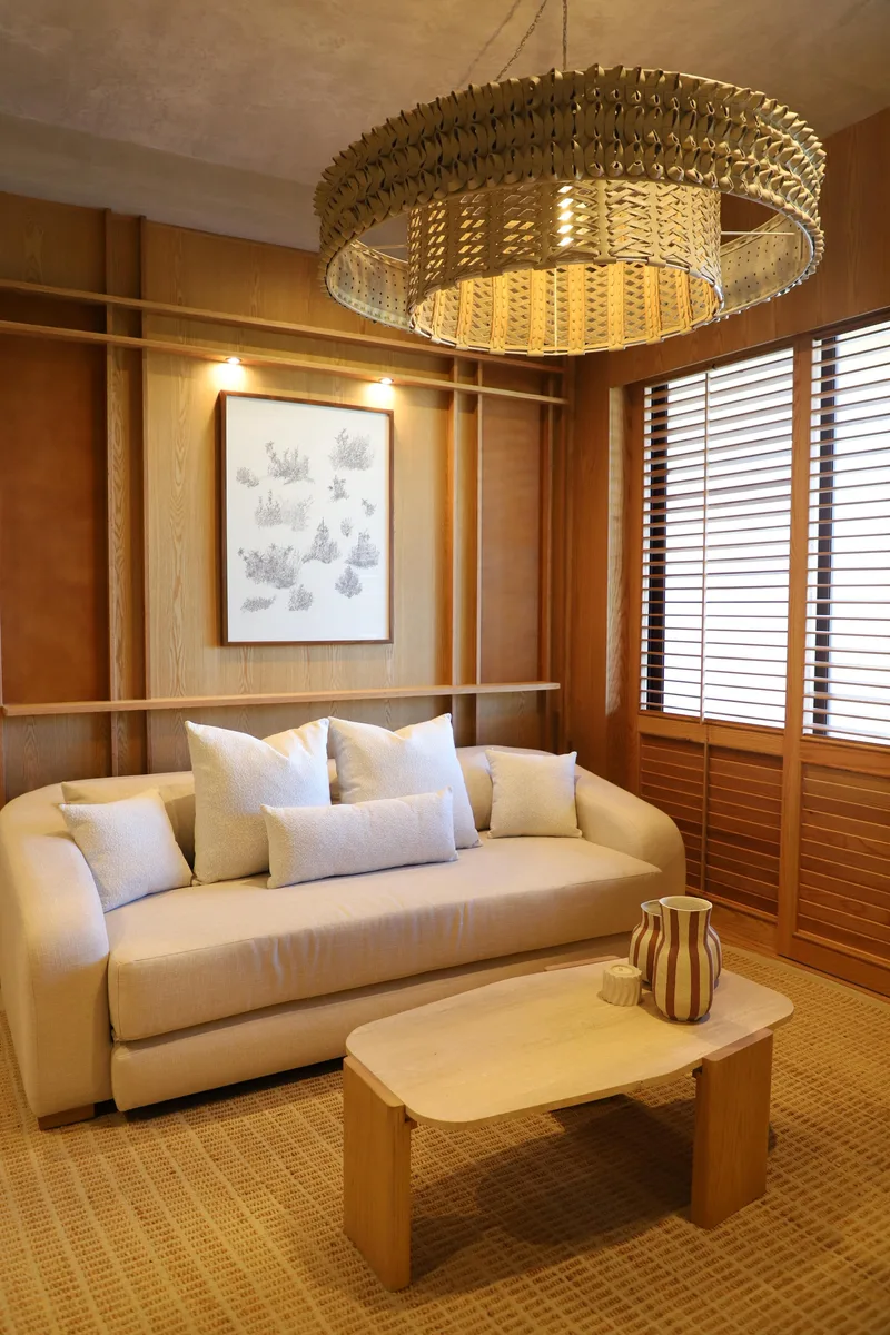Sala con lampara de anillo, sofa claro y persianas de madera