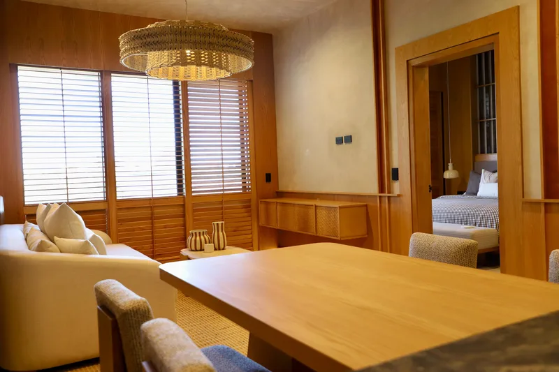 Comedor de madera junto a la sala, iluminado por una lampara circular