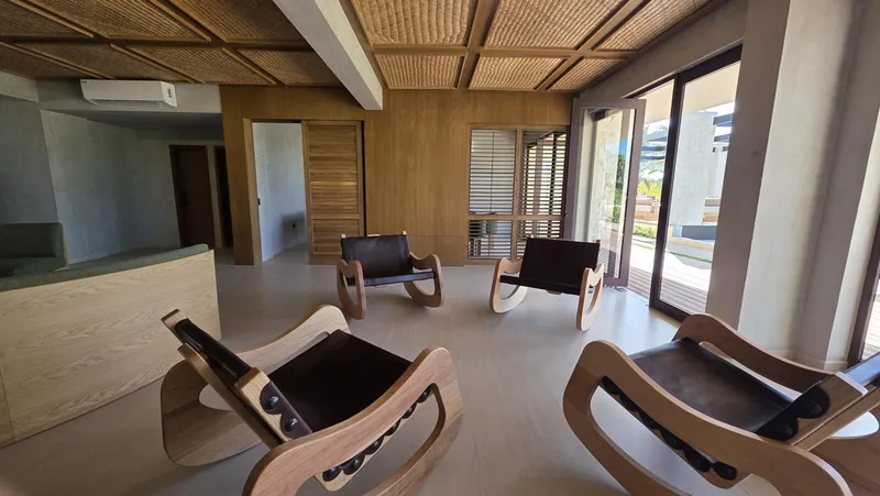 Sala del club con sillones de madera y ventanales hacia el jardin