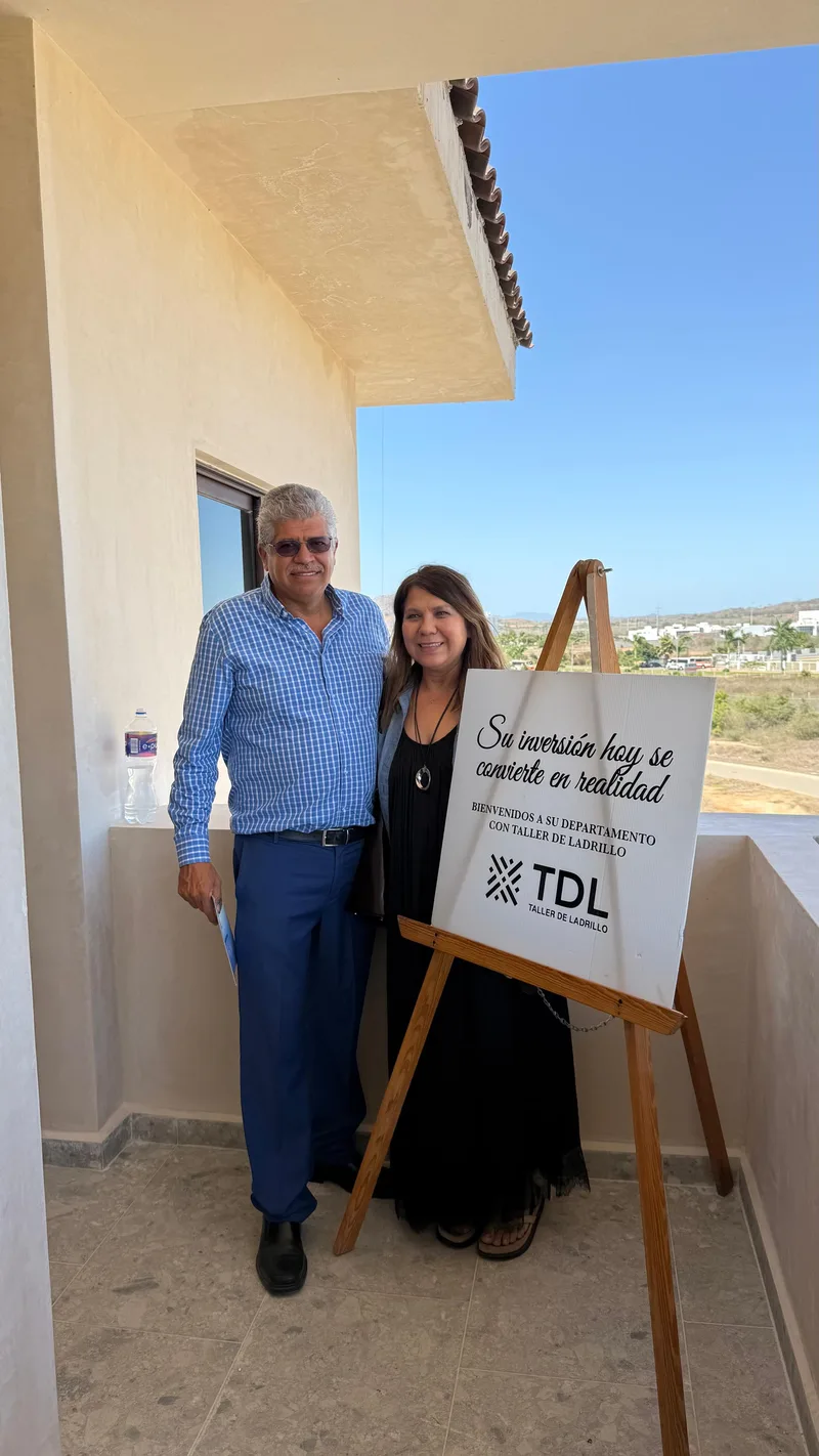 Propietarios junto al atril de bienvenida en la entrega de su departamento