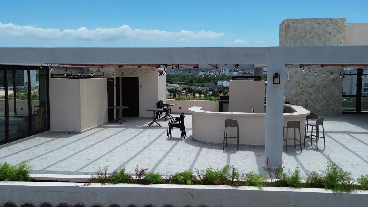 Bar y área social en el rooftop de Mangata, con barra curva y vista a Marina Mazatlán