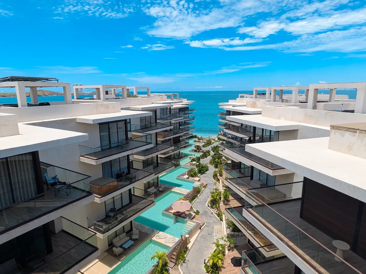 Condominios de Aldea Ananta abiertos al mar, con las albercas escalonadas del andador central entre las dos hileras de edificios